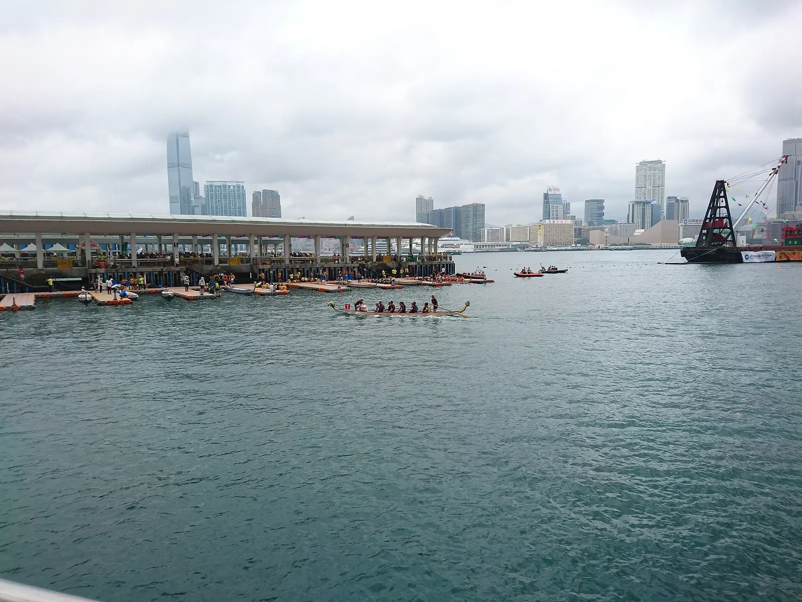 A dragon boat racing across Victoria Harbour with the Kowloon skyline behind