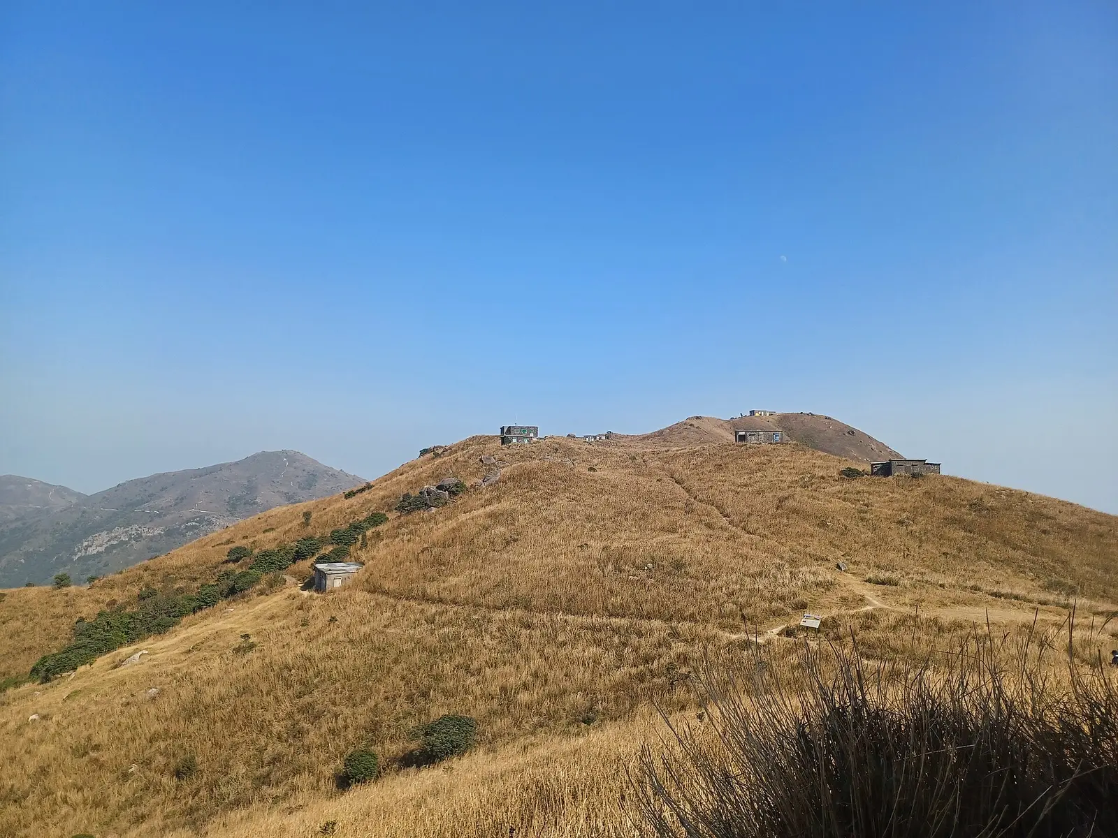 Dry grass hillsides along the Lantau Trail under a blue sky