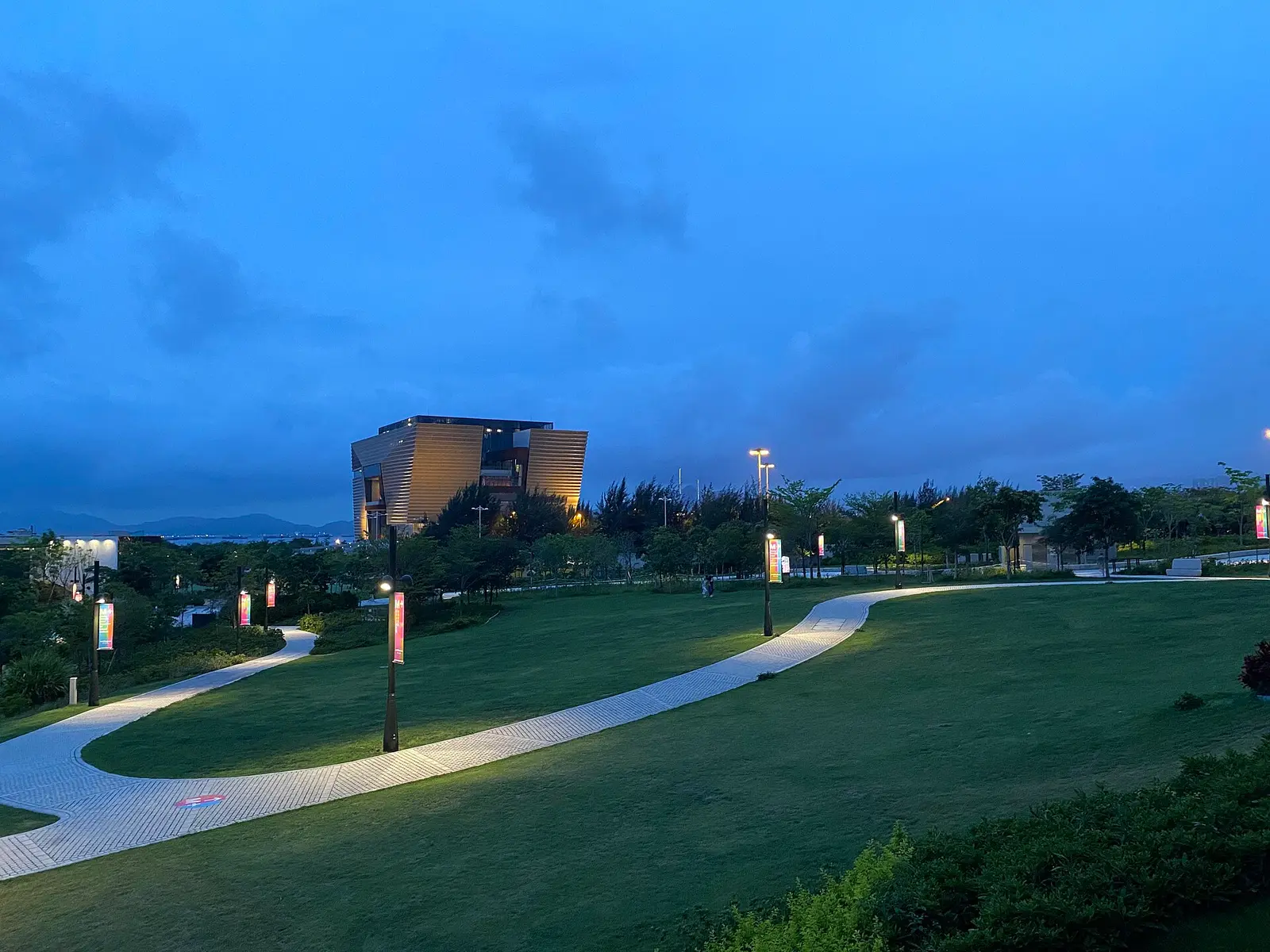 The M+ building seen across the park of the West Kowloon Cultural District at dusk